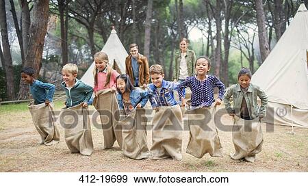 Stock Photo - Children having sack race at campsite. Fotosearch