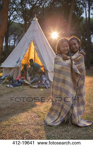 Stock Image - Children wrapped in blanket at campsite. Fotosearch