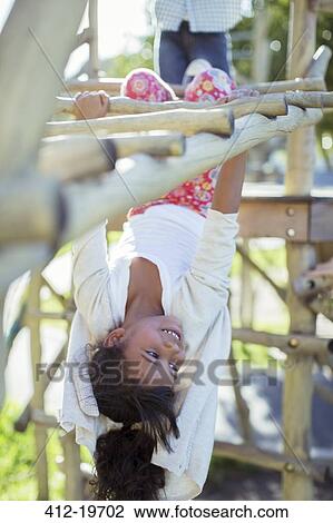 Girl climbing on monkey bars on playground View Large Photo Image Stock Image - Girl climbing on monkey bars on playground. Fotosearch
