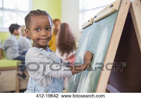 Girl drawing on chalkboard in classroom View Large Photo Image Stock Image - Girl drawing on chalkboard in classroom. Fotosearch