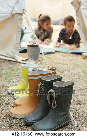 Stock Image - Rainboots lined up outside tent at campsite. Fotosearch