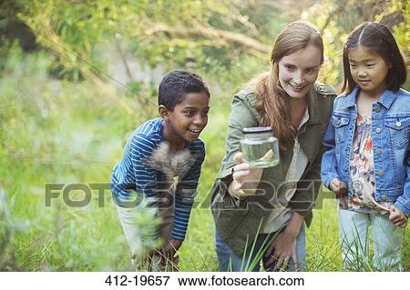 Student and teacher examining insect in jar View Large Photo Image Stock Photo - Student and teacher examining insect in jar. Fotosearch