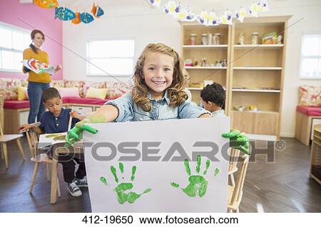 Stock Image - Student holding finger painting in class. Fotosearch