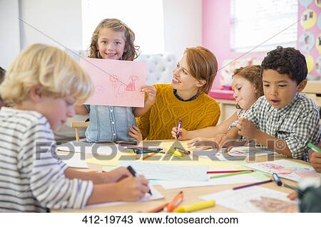Student showing off drawing in classroom View Large Photo Image Stock Image - Student showing off drawing in classroom. Fotosearch