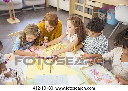 Stock Image - Students and teacher drawing in classroom. Fotosearch