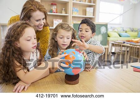 Students and teacher examining globe in classroom View Large Photo Image Stock Image - Students and teacher examining globe in classroom. Fotosearch