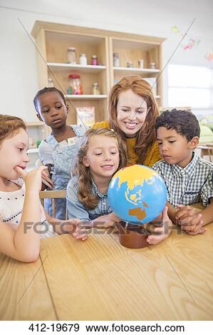Students and teacher examining globe in classroom View Large Photo Image Stock Photo - Students and teacher examining globe in classroom. Fotosearch