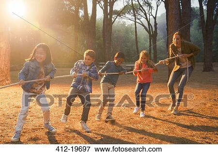 Stock Photo - Students and teacher playing tug of war in forest. Fotosearch