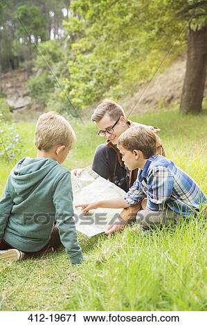 Stock Image - Students and teacher reading map in field. Fotosearch