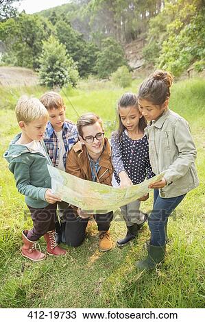 Stock Image - Students and teacher reading map in field. Fotosearch