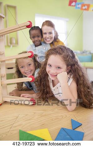 Stock Image - Students and teacher smiling in classroom. Fotosearch