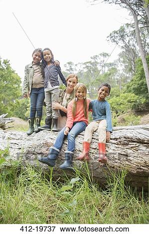 Students and teacher smiling on wooden log View Large Photo Image Stock Photo - Students and teacher smiling on wooden log. Fotosearch