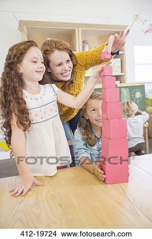 Picture - Students and teacher stacking blocks in classroom. Fotosearch