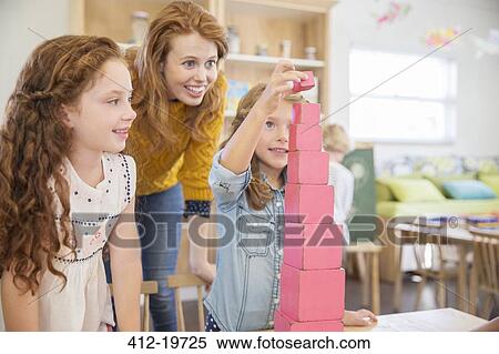 Stock Photography - Students and teacher stacking blocks in classroom. Fotosearch