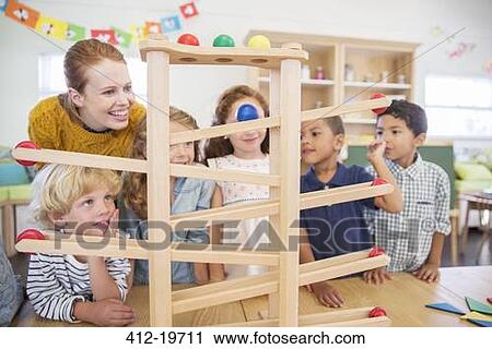 Stock Image - Students and teacher using model in classroom. Fotosearch