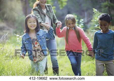 Stock Image - Students and teacher walking in forest. Fotosearch