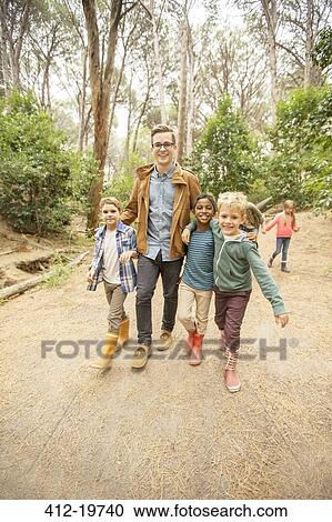 Stock Image - Students and teacher walking in forest. Fotosearch