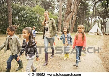 Stock Image - Students and teacher walking on dirt path. Fotosearch