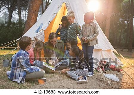 Teacher and students reading at campsite View Large Photo Image Stock Image - Teacher and students reading at campsite. Fotosearch