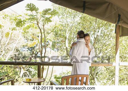 Stock Photo - Couple in bathrobes hugging on balcony. Fotosearch