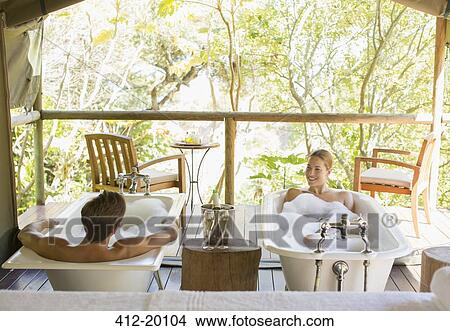 Picture - Couple in twin bathtubs in outdoor spa. Fotosearch
