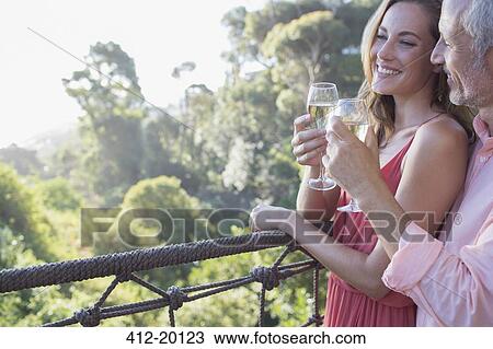 Couple toasting each other on balcony View Large Photo Image Stock Image - Couple toasting each other on balcony. Fotosearch