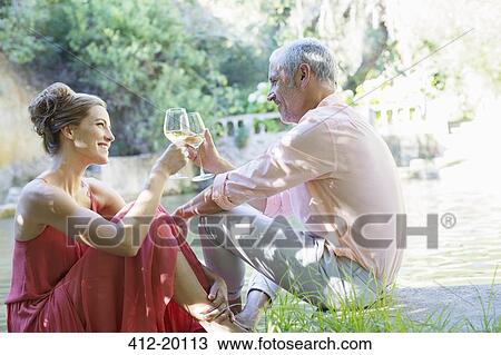 Stock Image - Couple toasting each other outdoors. Fotosearch