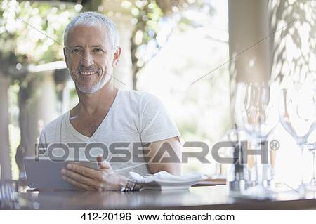 Stock Photograph - Man using digital tablet at table. Fotosearch