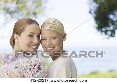 Stock Photo - Smiling women hugging indoors. Fotosearch