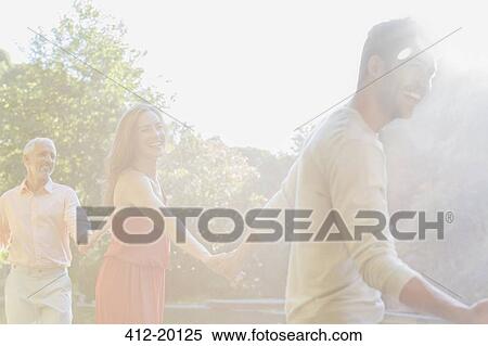 Stock Photography - Sunbeam over friends holding hands outdoors. Fotosearch