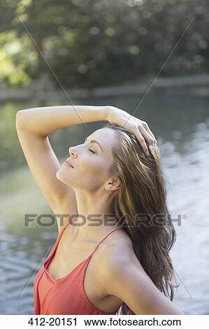 Stock Image - Woman relaxing by pond. Fotosearch