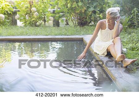 Stock Image - Woman relaxing by pool. Fotosearch