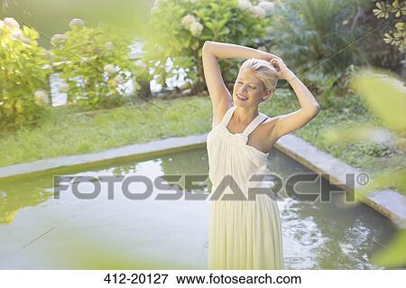 Woman standing by pool outdoors View Large Photo Image Stock Photo - Woman standing by pool outdoors. Fotosearch