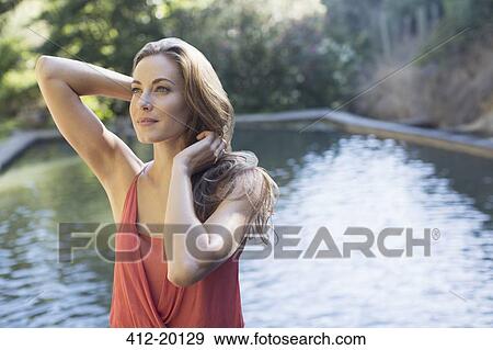 Stock Photo - Woman standing by pool outdoors. Fotosearch