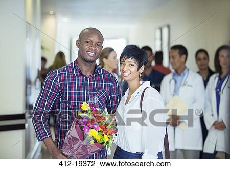 Couple carrying bouquet of flowers in hospital View Large Photo Image Stock Image - Couple carrying bouquet of flowers in hospital. Fotosearch