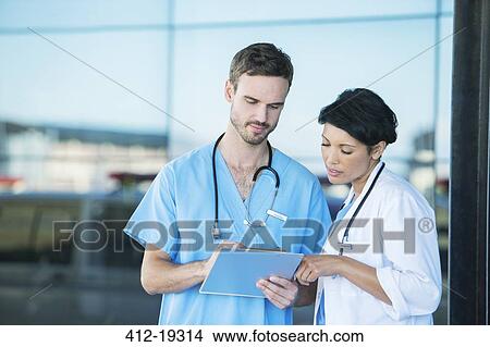 Picture - Doctor and nurse reading medical chart outdoors. Fotosearch