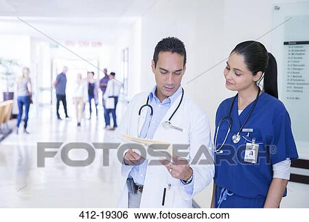 Doctor and nurse reading medical chart in hospital hallway View Large Photo Image Stock Photograph - Doctor and nurse reading medical chart in hospital hallway. Fotosearch