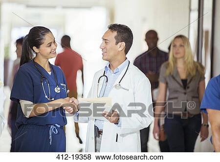 Stock Photo - Doctor and nurse shaking hands in hospital hallway. Fotosearch