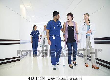 Doctor and nurse walking patient down hospital hallway View Large Photo Image Stock Image - Doctor and nurse walking patient down hospital hallway. Fotosearch