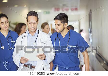Doctor and nurses reading medical chart in hospital hallway View Large Photo Image Stock Image - Doctor and nurses reading medical chart in hospital hallway. Fotosearch