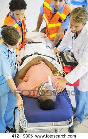 Stock Photography - Doctor, nurse and paramedics examining man on stretcher. Fotosearch