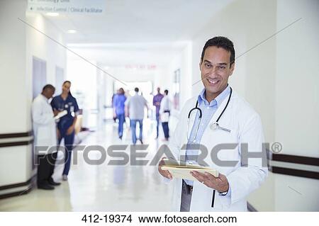 Doctor smiling in hospital hallway View Large Photo Image Picture - Doctor smiling in hospital hallway. Fotosearch