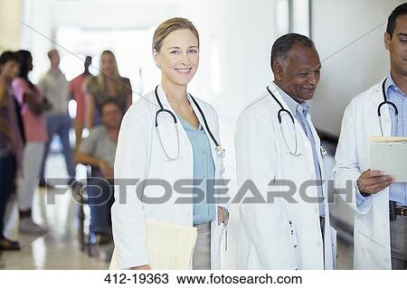 Stock Image - Doctor smiling in hospital hallway. Fotosearch
