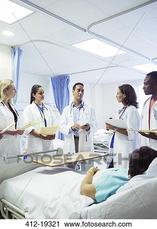 Stock Image - Doctor teaching residents in hospital room. Fotosearch