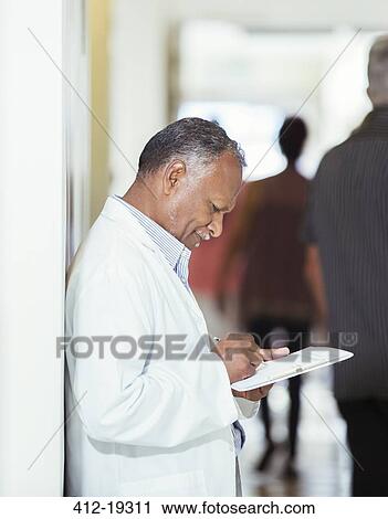 Doctor writing on medical chart in hospital View Large Photo Image Stock Image - Doctor writing on medical chart in hospital. Fotosearch