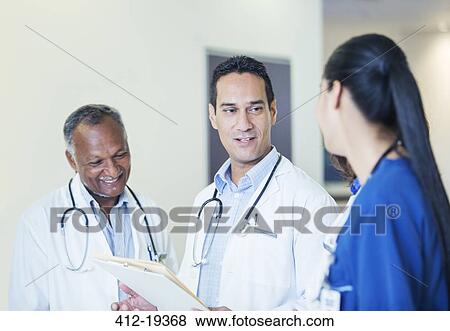 Doctors and nurse talking in hospital hallway View Large Photo Image Stock Photo - Doctors and nurse talking in hospital hallway. Fotosearch