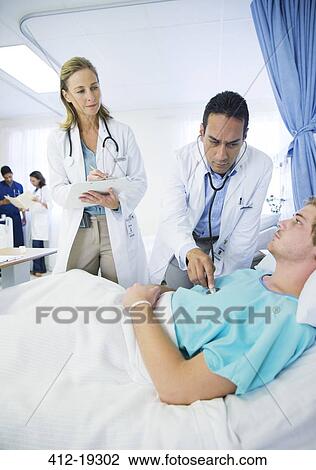 Doctors examining patient in hospital room View Large Photo Image Stock Image - Doctors examining patient in hospital room. Fotosearch
