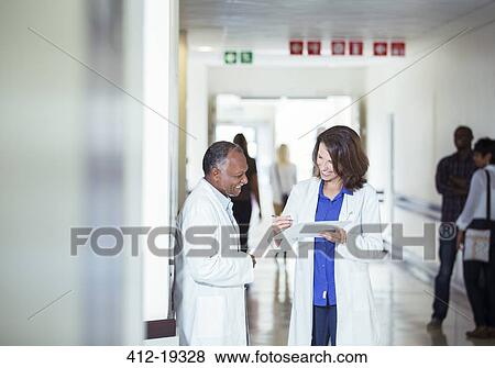 Stock Photo - Doctors reading medical chart in hallway. Fotosearch
