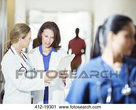 Doctors reading medical chart in hospital hallway View Large Photo Image Stock Image - Doctors reading medical chart in hospital hallway. Fotosearch