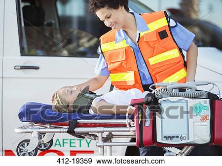Paramedic examining patient on stretcher View Large Photo Image Stock Photo - Paramedic examining patient on stretcher. Fotosearch